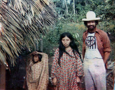Jeff Lewis standing next to two Mayan women outside a thatched hut in the the Lacandon Rain forest
